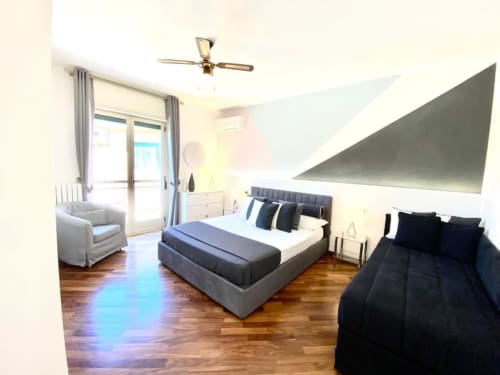 Camera elegante della Mottola Apartments a Tropea con letti matrimoniali, divano e balcone con vista sul giardino