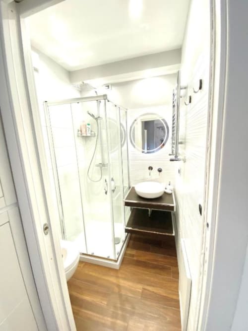 Moderno bagno nella Superior Suite di Mottola Apartments Tropea con cabina doccia, specchio rotondo e pavimentazione in legno