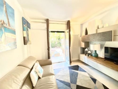 Elegante soggiorno dell'Appartamento Deluxe di Mottola Apartments a Tropea: divano beige, TV schermo piatto, angolo cottura e giardino