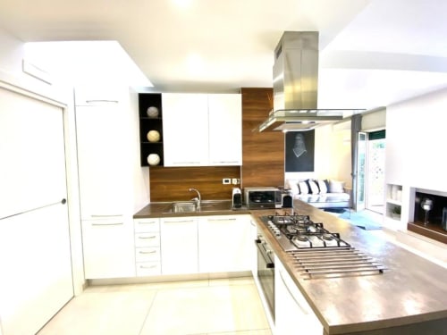 Cucina moderna nell'Appartamento Superior di Mottola Apartments, Tropea con mobili bianchi, piano cottura a gas e acciaio inox
