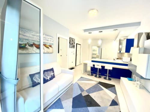 Interno moderno degli Appartamenti Mottola a Tropea con accenti blu, cucina bianca, area living e pavimento geometrico