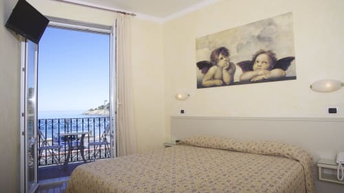 Camera soleggiata all'Hotel Feluca di Bonassola con balcone affacciato sul mare, letto matrimoniale e decorazioni con cherubini