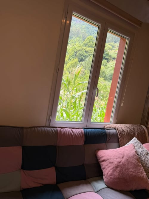 Aconchego acolhedor com sofá patchwork vista para jardins montanhosos luxuriantes em Refúgio do Nevoeiro, São Vicente