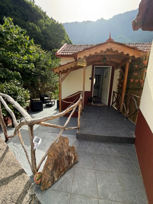 Chalé Cantinho do Urzal no Refúgio do Nevoeiro com varanda de madeira, telhado de telha vermelha, vistas das montanhas e jardim paisagístico