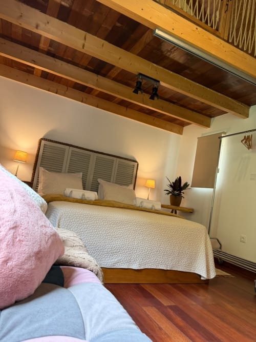 Quarto aconchegante na pousada Refúgio do Nevoeiro em São Vicente, com vigas de madeira, roupa de cama branca e vistas para a montanha