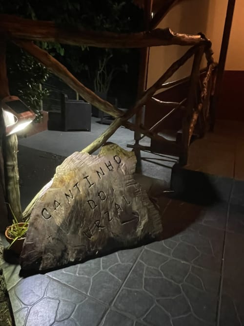 Banco de madeira com texto esculpido na área do jardim da quinta Cantinho do Urzal, retiro na serra de São Vicente