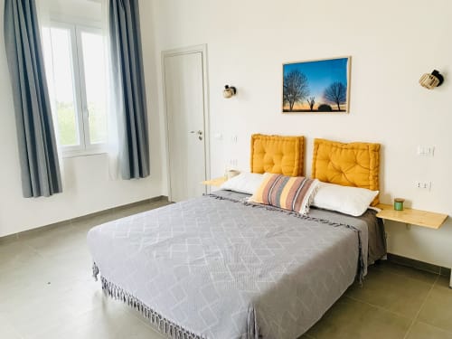 Luminosa camera da letto presso Ca' Salino B&B con testiera trapuntata gialla, biancheria bianca e vista sul giardino a Villa Inferno, Italia