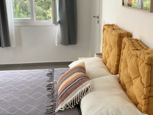 Camera accogliente del Ca' Salino B&B con testata in trapuntato giallo senape, cuscini bianchi, cuscino rigato e finestra con vista giardino
