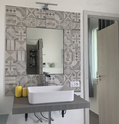 Raffinato mobile bagno a Ca' Salino con lavabo in ceramica bianca, piastrelle geometriche e specchio presso Villa Inferno