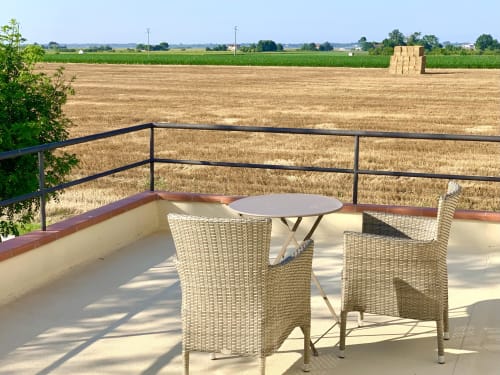 Terrazza di Ca' Salino con vista sui campi mietuti di Villa Inferno, Italia, arredata con sedie e tavolo in vimini