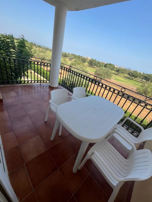 Terraza soleada con mobiliario blanco con vistas a olivares, apartamento Home Guardian Services en Sant Jordi