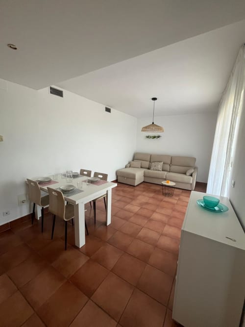 Salón comedor moderno en el apartamento OLIVOS DEL SOL, Sant Jordi, con pisos de barro, sofá beige y comedor blanco