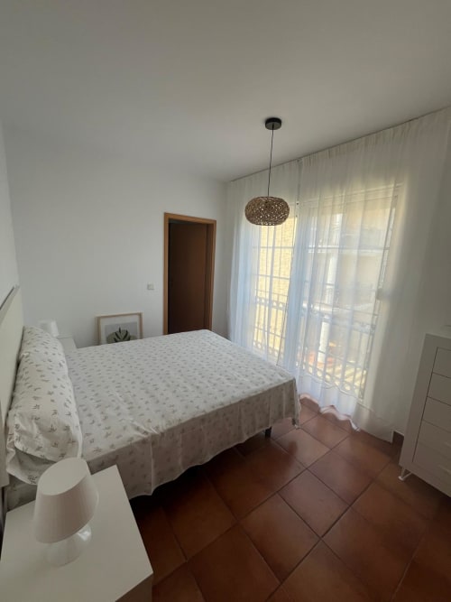 Habitación luminosa en Home Guardian Services, Sant Jordi, con cama doble, azulejos de terracota, lámpara colgante y vista al jardín