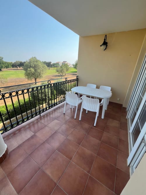 Terraza con mesa y sillas blancas con vistas a olivares y campos verdes en Sant Jordi