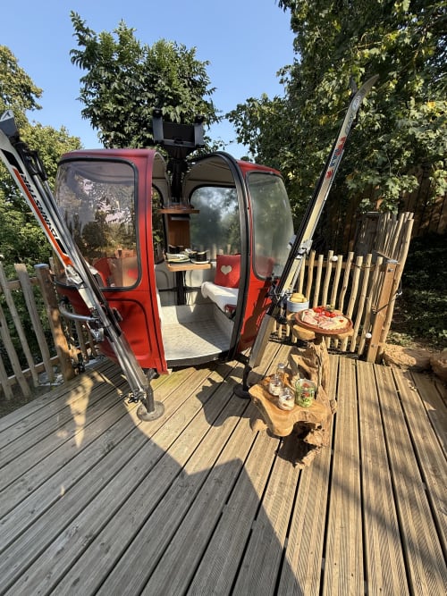 Camion aménagé rouge transformé en refuge douillet au Cœur de lodge B&B à Cramoisy, avec espace de restauration extérieure et skis