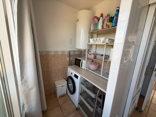 Lavadero con lavadora, microondas y estanterías de almacenamiento en el apartamento Sant Jordi