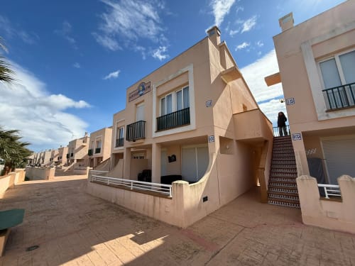 Casas adosadas beige del complejo Sant Jordi con cielo azul, con balcones y aparcamientos a nivel de calle