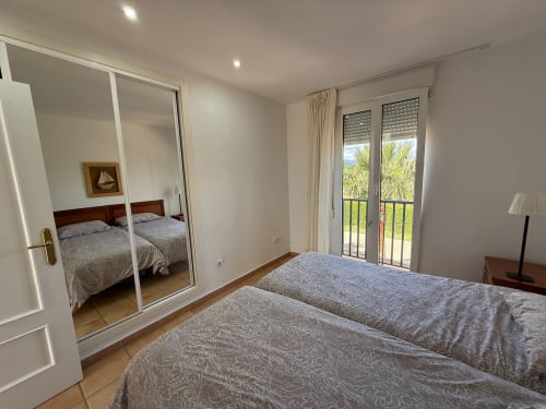 Dormitorio moderno con armario espejado, camas gemelas y balcón con vistas a palmeras y campo de golf en Sant Jordi