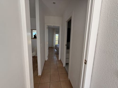 Pasillo moderno del apartamento Sant Jordi con piso de baldosas de terracota, puertas blancas y vistas al jardín
