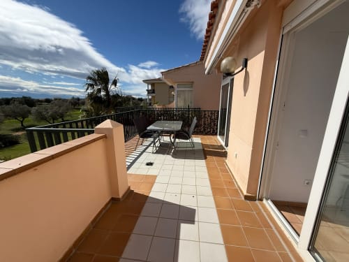 Terraza soleada con vistas al campo de golf, apartamento Sant Jordi con mesa de comedor y paisaje rural