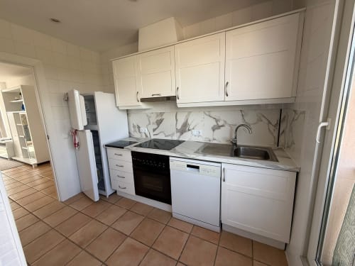Cocina blanca moderna con azulejos de mármol, electrodomésticos y fregadero en apartamento Sant Jordi con vistas al jardín