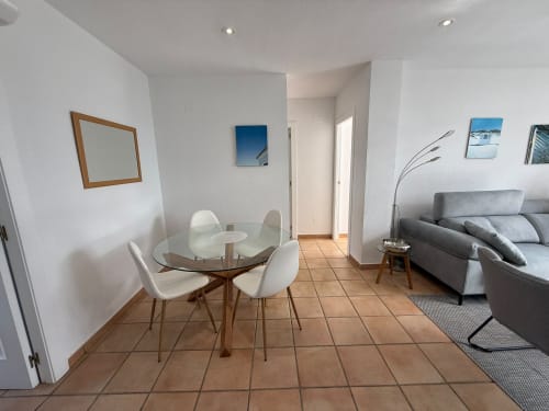 Moderna sala de estar en Sant Jordi con mesa de comedor, sofá gris, suelo de terracota y acceso al pasillo