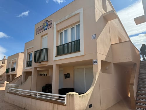 Edificio beige en Sant Jordi con balcones, unidades numeradas 131, vistas al jardín y estacionamiento en calle