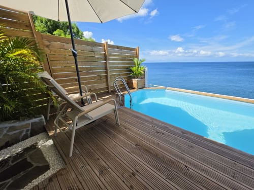 Oceanfront infinity pool deck at Clémara Evasion with lounger, umbrella, and Caribbean Sea view in Schœlcher