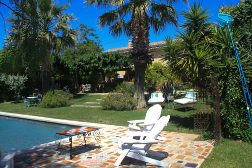 Terrasse ensoleillée de la piscine du Clos B&B à Saint-Cyr sur Mer avec transats, palmiers et villa méditerranéenne