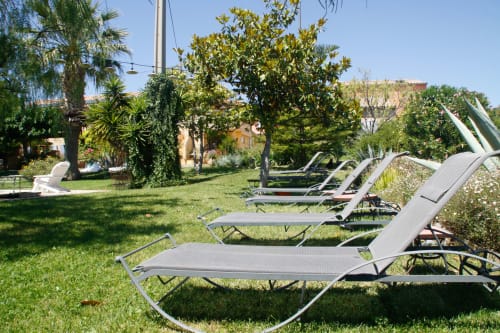 Chaises longues sur la pelouse ensoleillée du Clos Bb à Saint-Cyr-sur-Mer, avec palmiers et architecture méditerranéenne