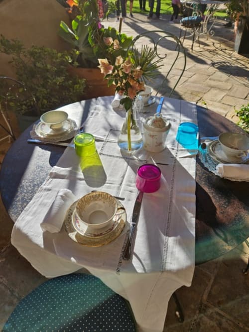 Table de salle à manger en plein air au Clos BB à Saint-Cyr sur Mer avec couverts, fleurs et boissons colorées