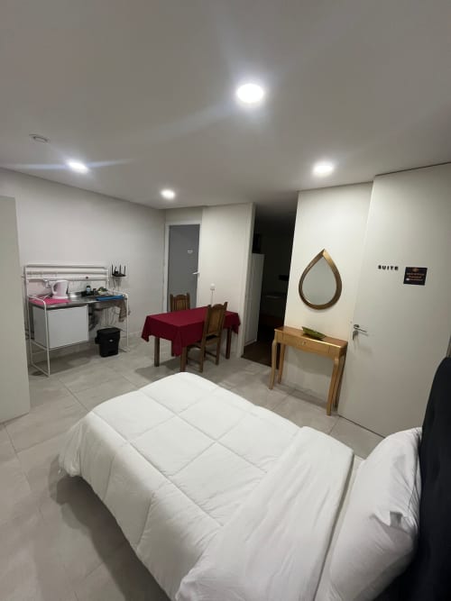 Suite do hostel Casa Augusta em Braga com cama, mesa de jantar, kitchenette e espelho