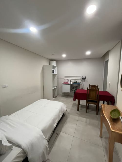 Suíte do hostel Casa Augusta em Braga com cama, mesa de refeições, kitchenette e armazenamento em quarto luminoso