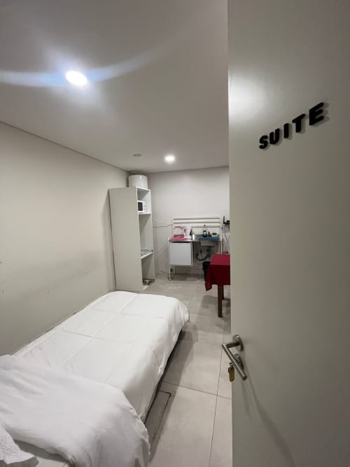 Suite da Pousada Casa Augusta em Braga com cama, máquina de lavar, kitchenete e armazenamento em layout compacto