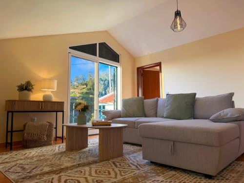 Modern living room at Check Madeira in Ribeira Brava with gray sofa, wooden furniture, and panoramic valley views
