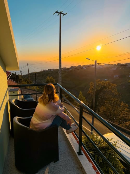 Woman enjoying sunset from balcony at Check Madeira hotel in Ribeira Brava, Portugal