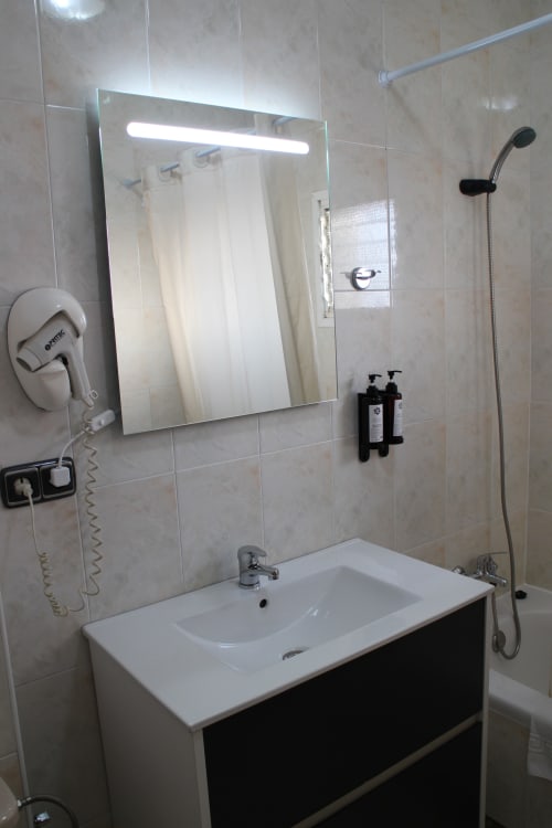 Cuarto de baño moderno en Mesón Hotel El 21 de Níjar con espejo iluminado, lavamanos blanco y accesorios de ducha