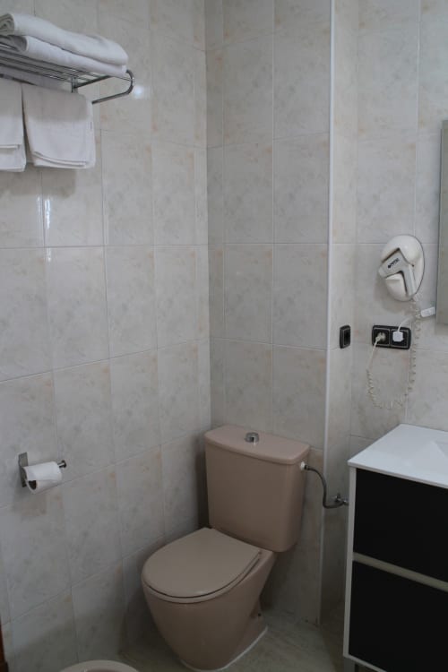 Baño del Mesón Hotel El 21 en Níjar con paredes alicatadas en beige, inodoro, lavamanos, toallero y área de ducha