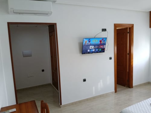 Habitación moderna del Mesón Hotel El 21 en Níjar con televisor de pantalla plana, puertas de madera y diseño accesible