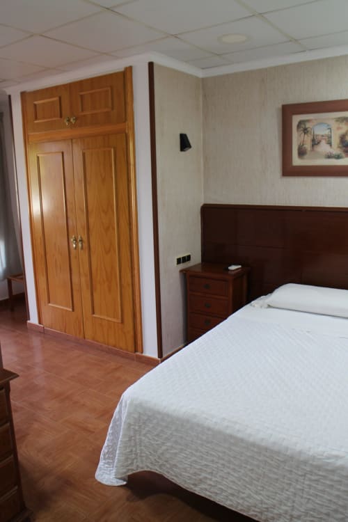 Habitación doble en Mesón Hotel El 21 de Níjar con cama, armario de madera y mesita de noche