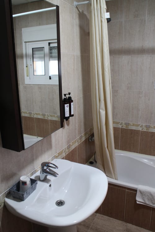 Baño moderno del Mesón Hotel El 21 en Níjar con lavamanos blanco, armario con espejo y paredes alicatadas