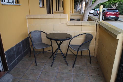 Patio exterior con dos sillas oscuras y mesa redonda en Mesón Hotel El 21, Níjar España