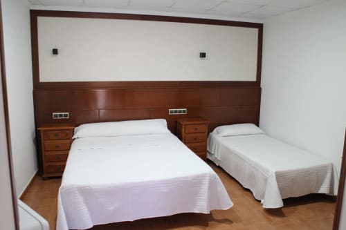Habitación triple en Mesón Hotel El 21 de Níjar con dos camas, muebles de madera y ropa blanca
