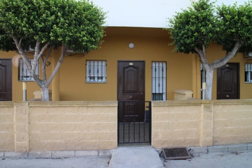 Entrada del Mesón Hotel El 21 en Níjar con fachada amarilla, puerta de madera oscura y pared de piedra