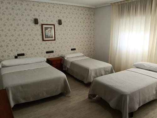 Habitación triple del Mesón Hotel El 21 en Níjar con tres camas y papel tapiz floral