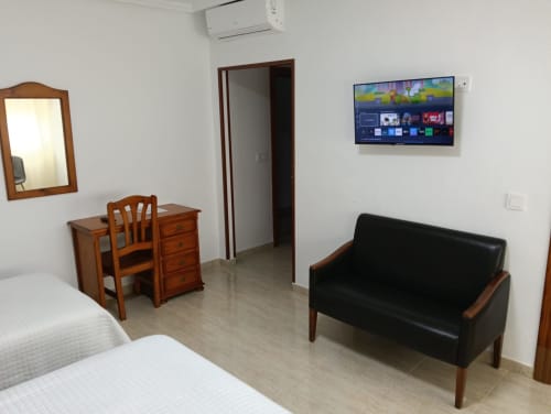 Habitación triple en Mesón Hotel El 21 en Níjar con cama, sofá, escritorio, TV y aire acondicionado