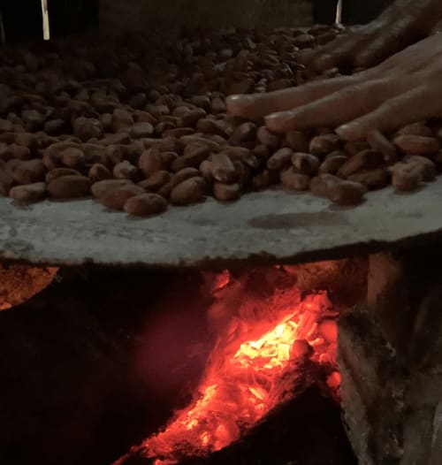 Acogedor fuego de campamento con granos de cacao tostados en el hotel Sento SanMa de San Mateo Rio Hondo, México