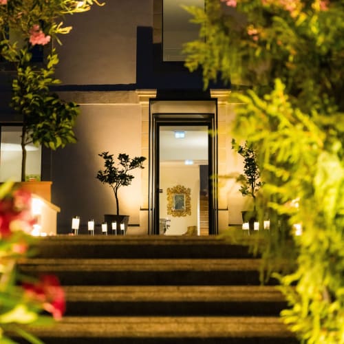 Entrée élégante de nuit du Domaine de la Peyrine à Carignan de Bordeaux, façade illuminée avec plantes décoratives