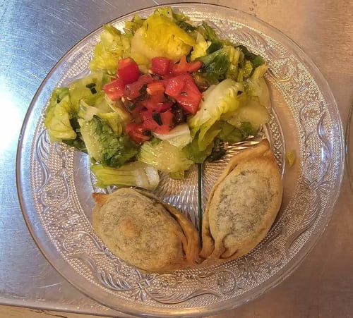 Plated dish at Aux Prés Du Berry with two empanadas, mixed greens, and red pepper garnish in Chavin, France