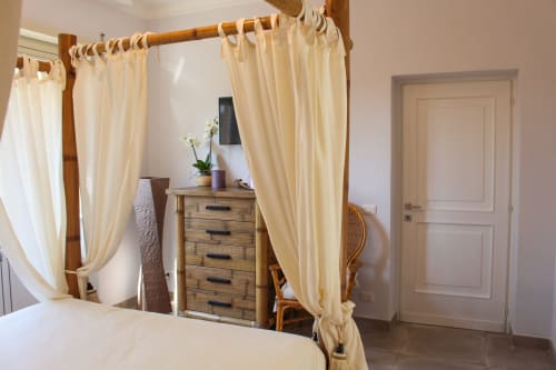 Spaziosa camera da letto a MAISON TIZI con letto a quattro colonne in legno, tende color crema, comò e vista sul giardino a Fiumicino Roma